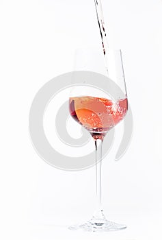 Rose wine pouring out of the bottle, white bakcground. Rosado, rosato or blush wine tasting in wineshop, bar concept. Copy Space