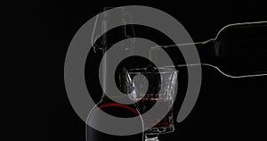 Rose wine. Red wine pour in wine glass over black background. Silhouette