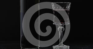 Rose wine. Red wine in wine glass with bottle over black background. Silhouette