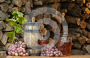 Rose wine in the wineglass and ripe grapes on wooden table