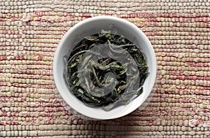 Rosebay willowherb fermented green tea in a white bowl on woven grey cotton fabric, closeup, traditional russian drink