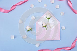 Rosebuds, petals, congratulatory envelope, on a blue background. Concept for a greeting card. Weddings, Valentine`s Day