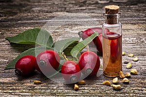 Rosehip seed oil Rosa canina; with  berries on wooden table. essential oil photo