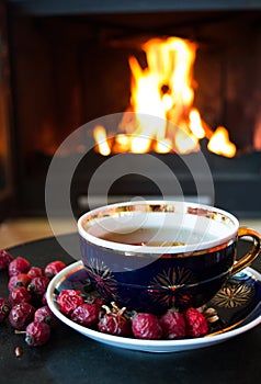Rosehip tea in front of roaring fire in a fire place