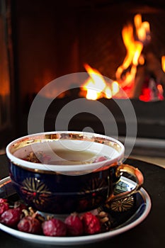 Rosehip tea in front of roaring fire in a fire place