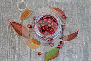 Rosehips in a glass jar on a wooden background