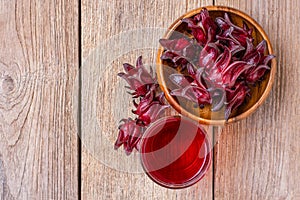 Roselle fruit  Jamaica sorrel, Rozelle or hibiscus sabdariffa  and glass of roselle juice tea isolated on wooden table backgroun