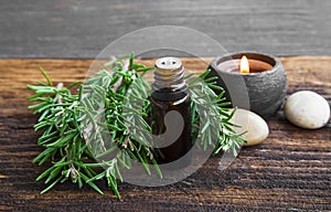 Rosemary aromatherapy oil with rosemary herb on wooden background with candle