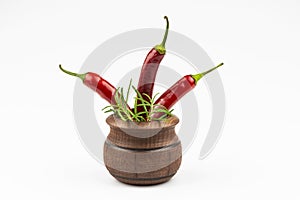 Rosemary branches, hot pepper in a wooden bowl isolated on a white background