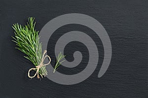 Rosemary bunch of bouquets on black stone surface. Top view, cop