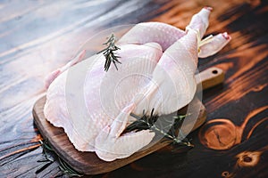 Rosemary chicken meat - fresh raw chicken whole on wooden board on white wood background