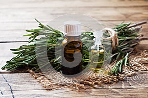 Rosemary essential oil in a glass bottle with fresh branch rosemary herb on wooden table for spa,aromatherapy and bodycare.Copy