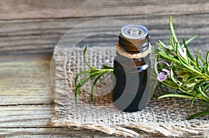 Rosemary essential oil in a glass dropper bottle with fresh green rosemary herb on old wooden table for spa,aromatherapy and body