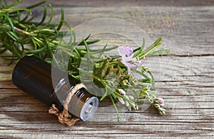 Rosemary essential oil in a glass dropper bottle with fresh green rosemary herb on old wooden table for spa,aromatherapy and bodyc