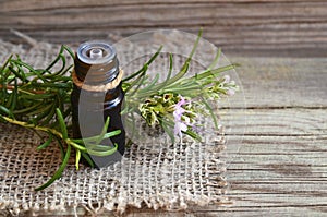 Rosemary essential oil in a glass dropper bottle with fresh green rosemary herb on old wooden table for spa,aromatherapy and bodyc