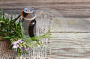 Rosemary essential oil in a glass dropper bottle with fresh green rosemary herb on old wooden table for spa,aromatherapy and bodyc