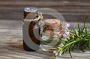 Rosemary essential oil in a glass dropper bottles with fresh green rosemary herb on old wooden table for spa,aromatherapy and body