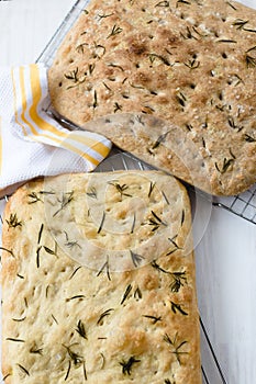Rosemary focaccia on a white surface and yellow kitchen towel