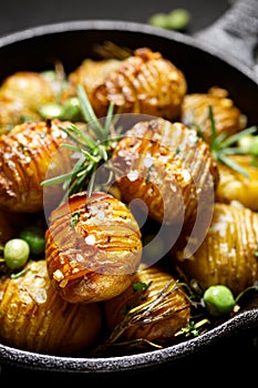 Rosemary and garlic roast potatoes with green peas on a cast iron pan