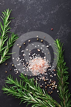 Rosemary, pink salt and spices on black stone table top view with copy space for menu or recipe, flat lay.