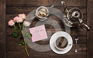 Roses and coffee. Cup of coffee, vintage silver coffeepot,  sugar bowl and a bouquet of roses on a wooden table. Morning coffee