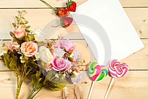 Roses flowers and empty tag for your text with heart-shaped candy on wooden background