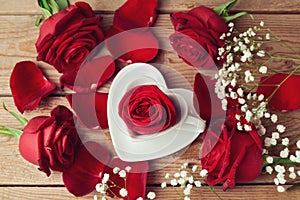 Roses with heart shape coffee cup on wooden background. View from above