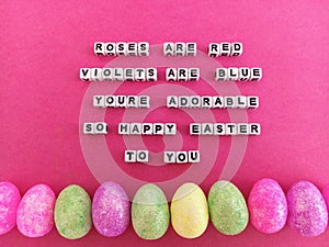 Roses are red violets are blue you're adorable so happy easter to you on a pink background with colorful Easter eggs