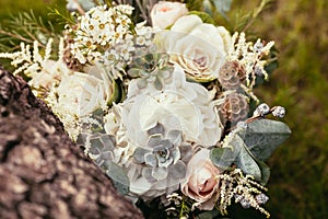 Roses, succulents and other flowers in wedding bouquet on green