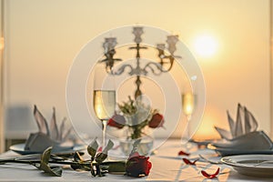 Roses on the table for the lover`s Valentine dinner With wine glasses and candlesticks. Sunset views on tall buildings.