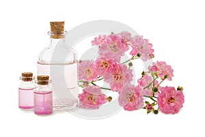 Roses water or oil in glass bottles and pink flowers isolated on white