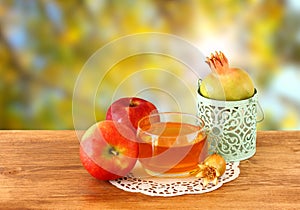 Rosh hashanah concept - apple honey and pomegranate over wooden table