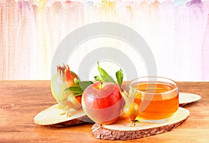 Rosh hashanah concept - apple honey and pomegranate over wooden table.