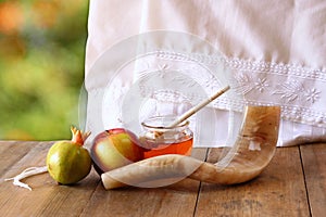 Rosh hashanah (jewesh holiday) concept - honey, apple and pomegranate over wooden table. traditional holiday symbols.