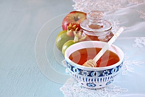 Rosh hashanah (jewesh holiday) concept - honey, apple and pomegranate over wooden table. traditional holiday symbols.