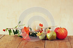 Rosh hashanah (jewesh holiday) concept - honey, apple and pomegranate over wooden table. traditional holiday symbols.