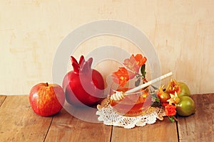 Rosh hashanah (jewesh holiday) concept - honey, apple and pomegranate over wooden table. traditional holiday symbols.