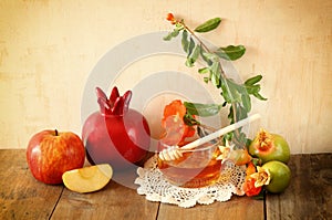 Rosh hashanah (jewesh holiday) concept - honey, apple and pomegranate over wooden table. traditional holiday symbols.