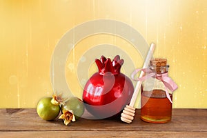 Rosh hashanah (jewesh holiday) concept - honey, apple and pomegranate over wooden table. traditional holiday symbols.