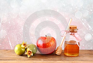 Rosh hashanah (jewesh holiday) concept - honey, apple and pomegranate over wooden table. traditional holiday symbols.