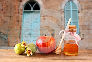 Rosh hashanah (jewesh holiday) concept - honey, apple and pomegranate over wooden table. traditional holiday symbols.