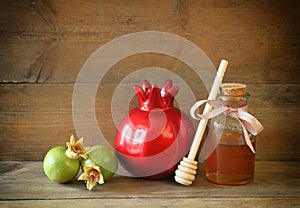 Rosh hashanah (jewesh holiday) concept - honey and pomegranate over wooden table. traditional holiday symbols.