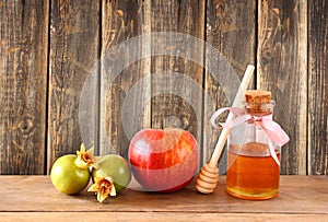 Rosh hashanah (jewesh holiday) concept - honey and pomegranate over wooden table. traditional holiday symbols.
