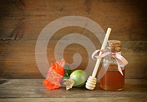 Rosh hashanah (jewesh holiday) concept - honey and pomegranate over wooden table. traditional holiday symbols.