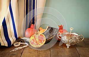 Rosh hashanah (jewesh holiday) concept - shofar, honey, apple and pomegranate over wooden table. traditional holiday symbols.