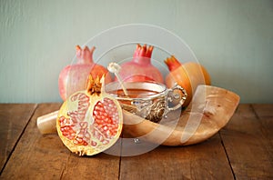 Rosh hashanah (jewesh holiday) concept - shofar, honey, apple and pomegranate over wooden table. traditional holiday symbols.