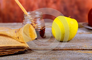 rosh hashanah jewesh holiday concept - shofar, torah book, honey, apple and pomegranate over wooden table. a kippah a yamolka