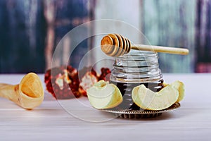 rosh hashanah jewesh holiday concept - shofar, torah book, honey, apple and pomegranate over wooden table. a kippah a yamolka