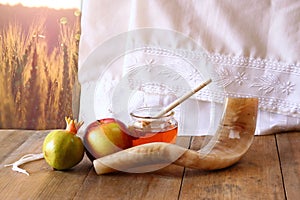 Rosh hashanah (jewesh holiday) concept - shofar, torah book, honey, apple and pomegranate over wooden table. traditional holiday