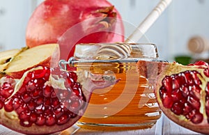 Rosh hashanah - jewish New Year holiday concept. Traditional symbols: Honey jar and fresh apples with pomegranate on white wooden